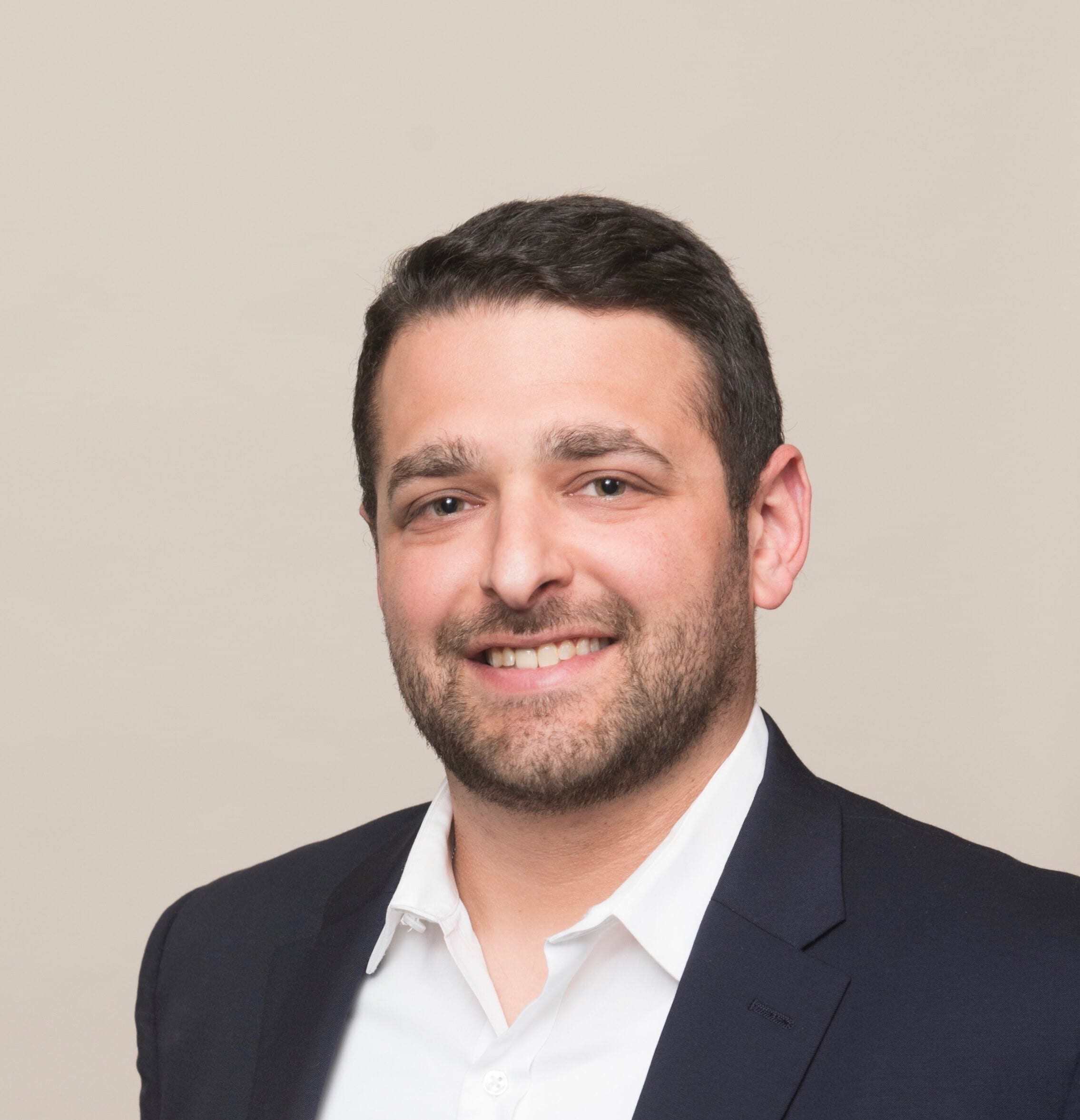 A man in a suit and white shirt smiles for the camera